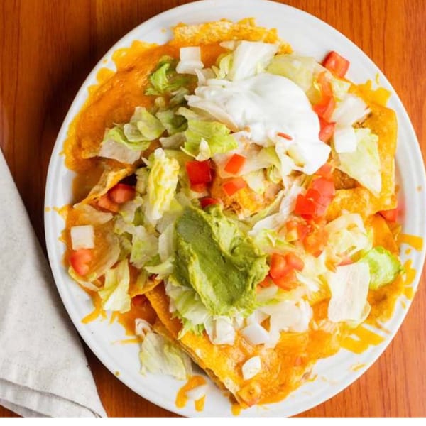 Moose Hill Cantina's Mexican enchiladas topped with lettuce, tomatoes, onions, guacamole, and sour cream.